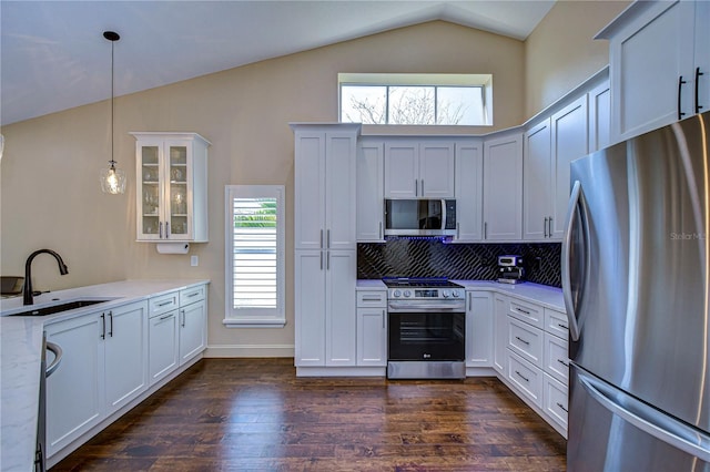 kitchen with dark wood-style floors, lofted ceiling, appliances with stainless steel finishes, glass insert cabinets, and a sink