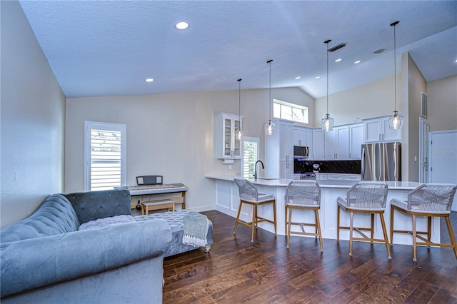 living area with high vaulted ceiling, dark wood-style flooring, and a textured ceiling