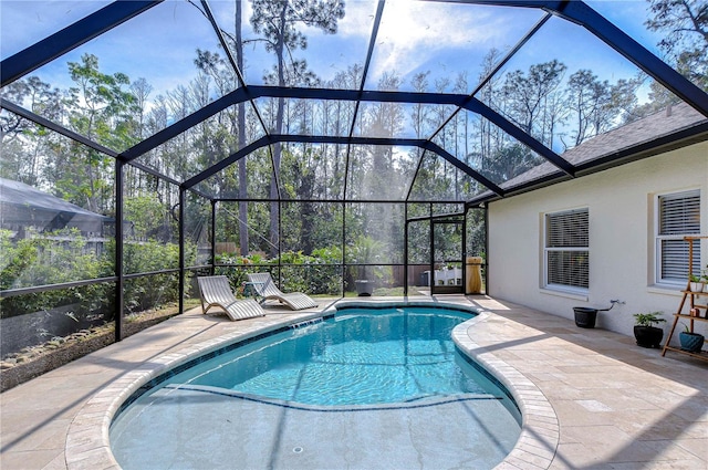 outdoor pool featuring glass enclosure and a patio