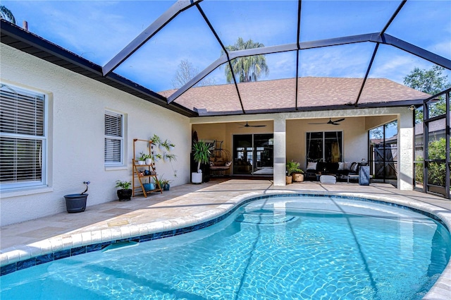 pool featuring glass enclosure, a ceiling fan, and a patio