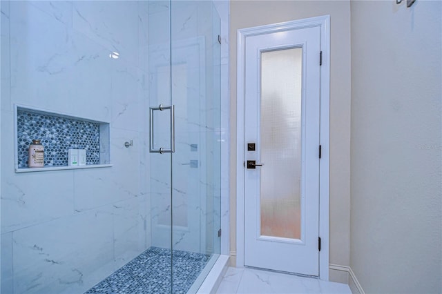 bathroom featuring marble finish floor, a marble finish shower, and baseboards