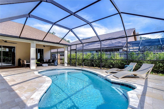 outdoor pool featuring glass enclosure, a patio area, and ceiling fan