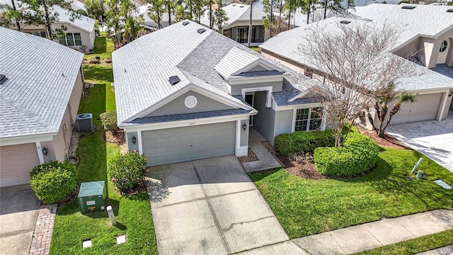 view of front of home with a garage, driveway, a shingled roof, and cooling unit