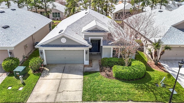 view of front facade with an attached garage, driveway, a front lawn, and roof with shingles