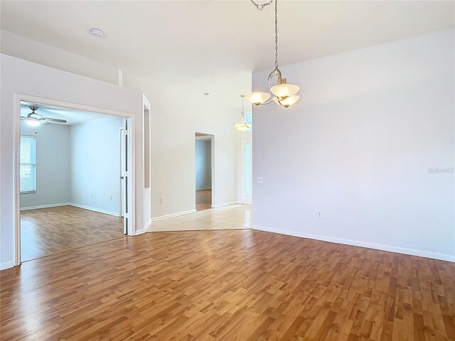 5351 Lookout Pass, Wesley Chapel, FL 33544 - empty room with ceiling fan with notable chandelier, light wood finished floors, and baseboards