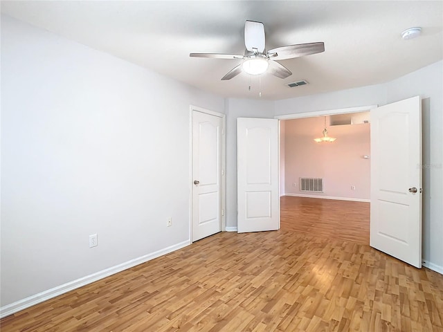 5351 Lookout Pass, Wesley Chapel, FL 33544 - empty room with visible vents, ceiling fan with notable chandelier, and light wood-style floors