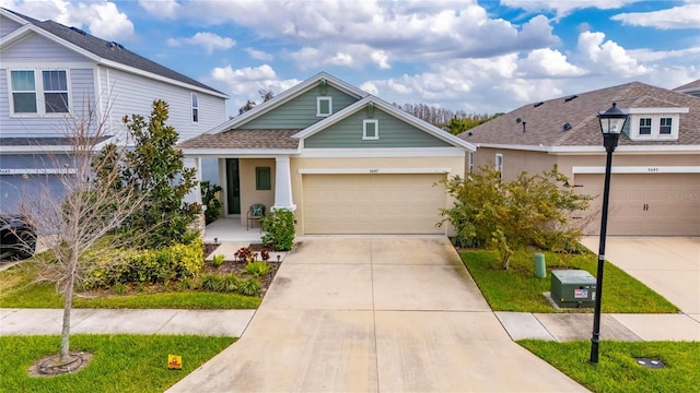 view of front of home with driveway, roof with shingles, an attached garage, and stucco siding