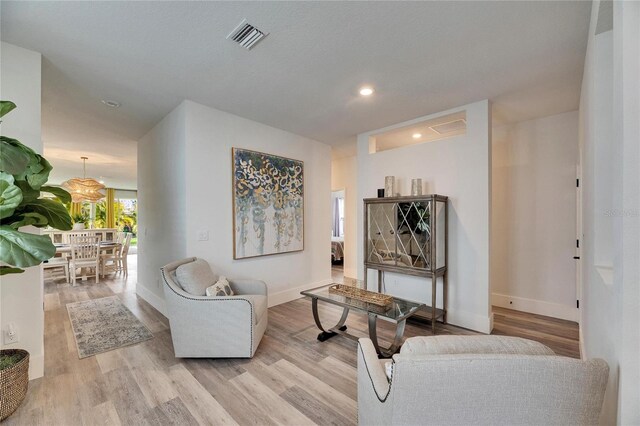 living area with recessed lighting, wood finished floors, visible vents, and baseboards