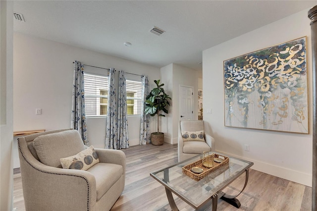 sitting room with light wood finished floors, baseboards, and visible vents