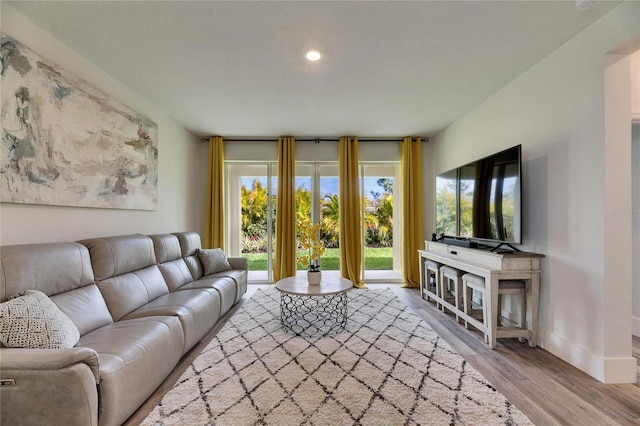 living room with a textured ceiling, recessed lighting, wood finished floors, and baseboards