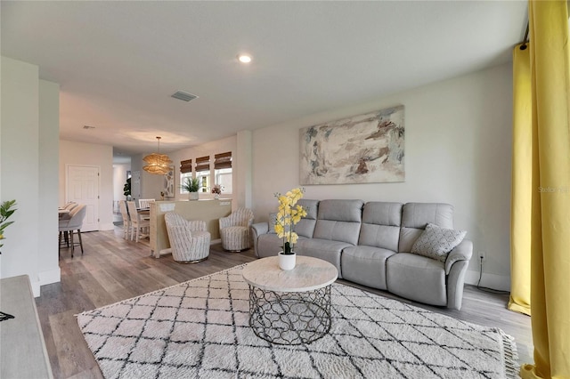 living area with recessed lighting, visible vents, baseboards, and wood finished floors