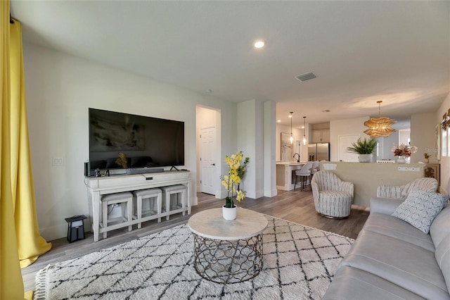 living room with recessed lighting, visible vents, baseboards, and wood finished floors