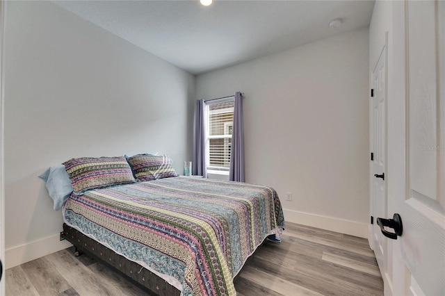 bedroom with baseboards and wood finished floors