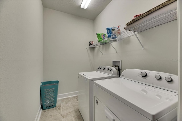 clothes washing area with laundry area, washing machine and dryer, and baseboards