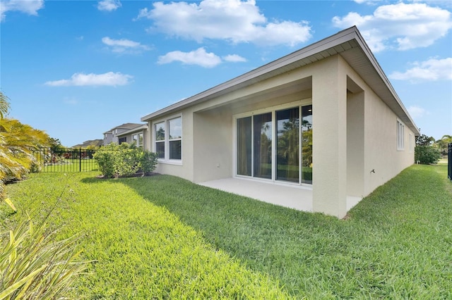 rear view of property with a yard, a patio, fence, and stucco siding