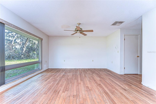 spare room featuring light wood-style floors, visible vents, a textured ceiling, and a ceiling fan