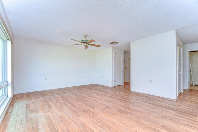 unfurnished room with a textured ceiling, ceiling fan, visible vents, and light wood-style flooring