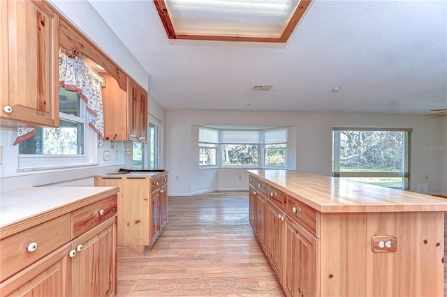 kitchen featuring butcher block counters, visible vents, a healthy amount of sunlight, light wood-style floors, and a center island