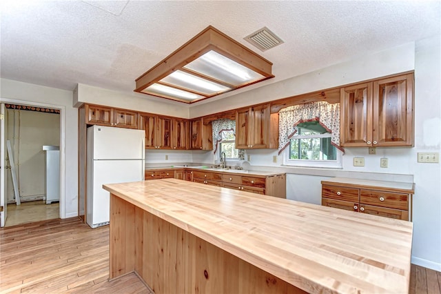 kitchen featuring a textured ceiling, butcher block counters, visible vents, light wood-style floors, and freestanding refrigerator