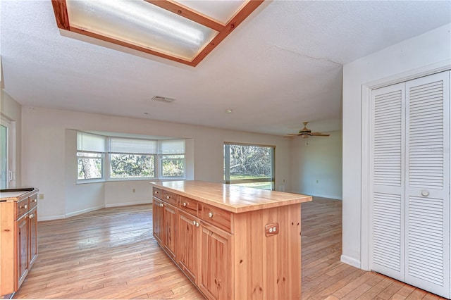 kitchen with a textured ceiling, light wood-type flooring, visible vents, and baseboards