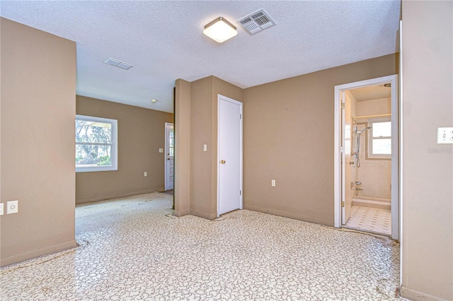 spare room with plenty of natural light, visible vents, and a textured ceiling