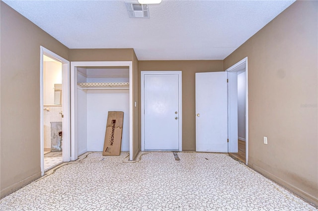 unfurnished bedroom with ensuite bath, visible vents, and a textured ceiling