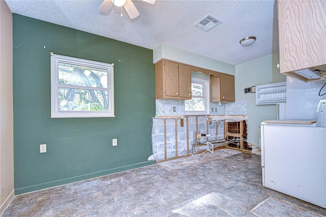 kitchen with ceiling fan, a textured ceiling, visible vents, baseboards, and washer / dryer