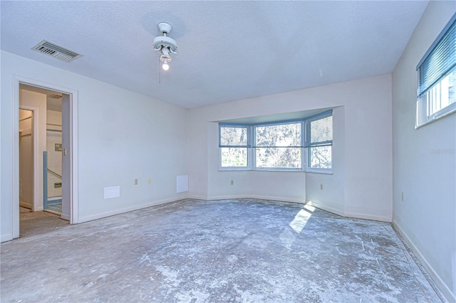 unfurnished room with baseboards, visible vents, and a textured ceiling