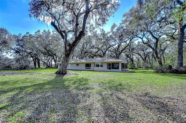 view of front of house with a front yard, a sunroom, and stucco siding