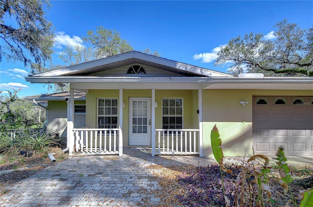 view of front of home with a porch, an attached garage, and stucco siding