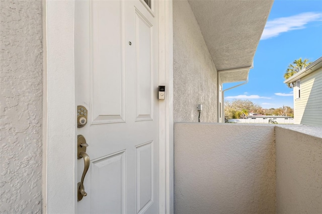 view of exterior entry featuring a balcony and stucco siding