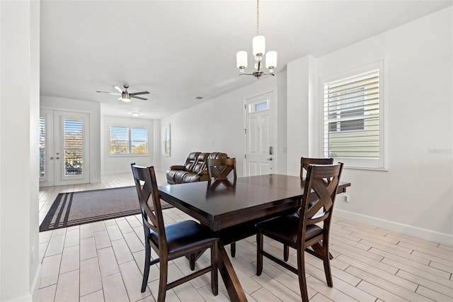 dining area featuring light wood-type flooring, baseboards, and ceiling fan with notable chandelier