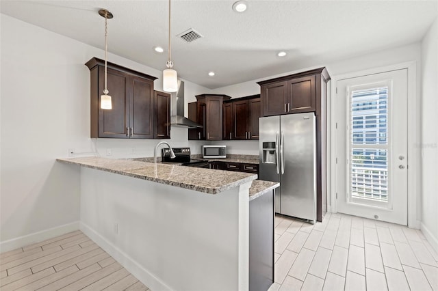 kitchen featuring stainless steel appliances, a peninsula, visible vents, dark brown cabinets, and wall chimney exhaust hood