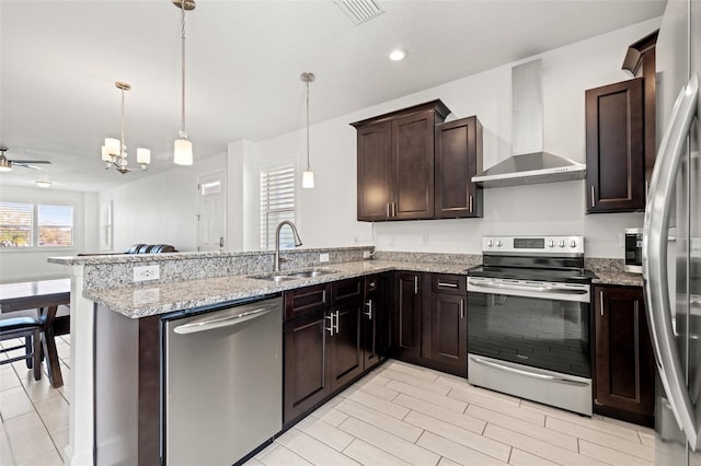 kitchen featuring visible vents, wall chimney exhaust hood, a peninsula, stainless steel appliances, and a sink