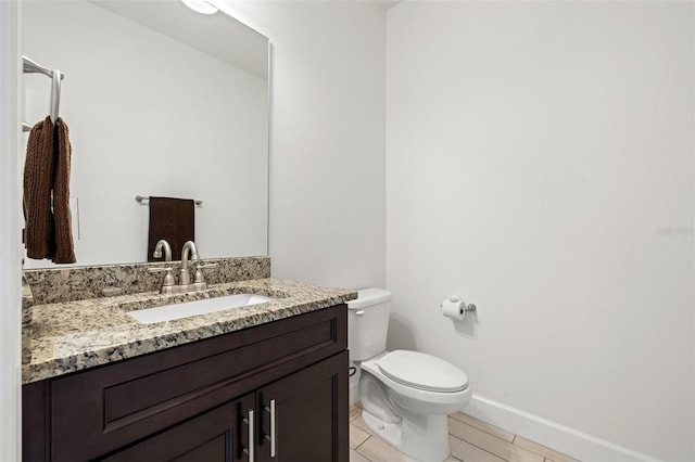 bathroom featuring toilet, baseboards, and vanity