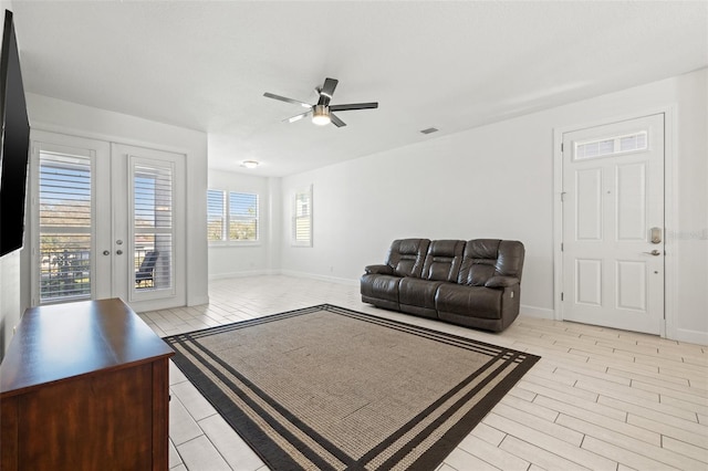 living room featuring visible vents, baseboards, ceiling fan, french doors, and light wood-style floors