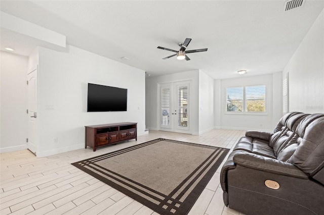 living area featuring a ceiling fan, light wood-type flooring, visible vents, and baseboards