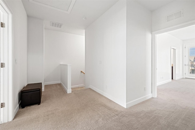 carpeted spare room with attic access, visible vents, and baseboards