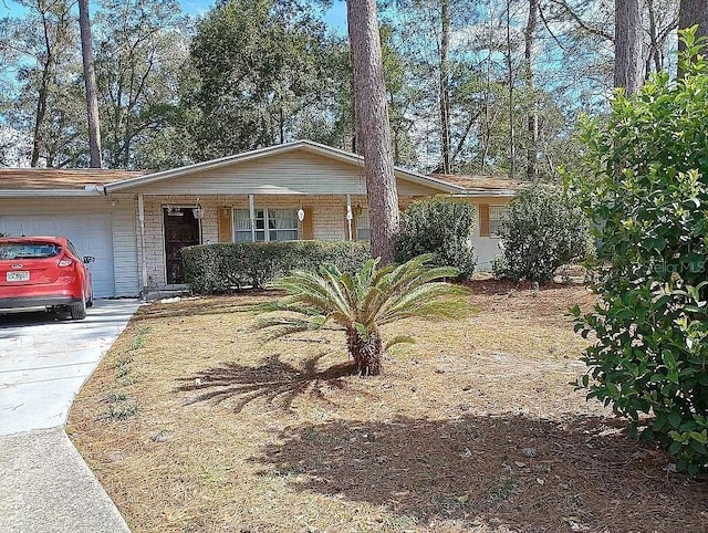 single story home featuring a garage, covered porch, driveway, and brick siding