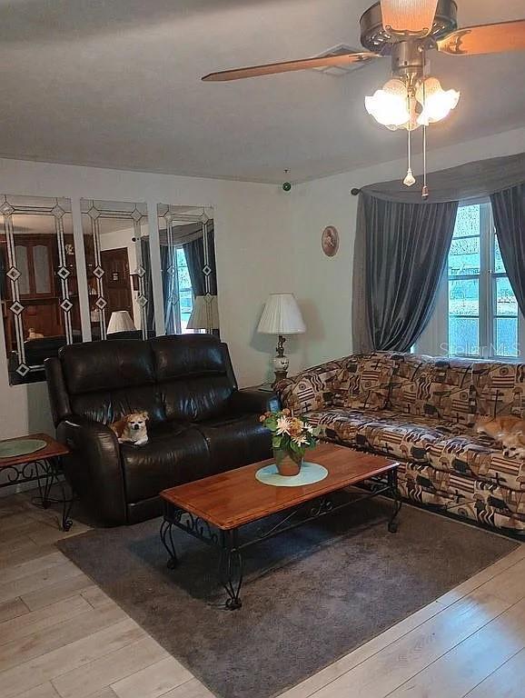 living room with light wood-type flooring, plenty of natural light, and ceiling fan