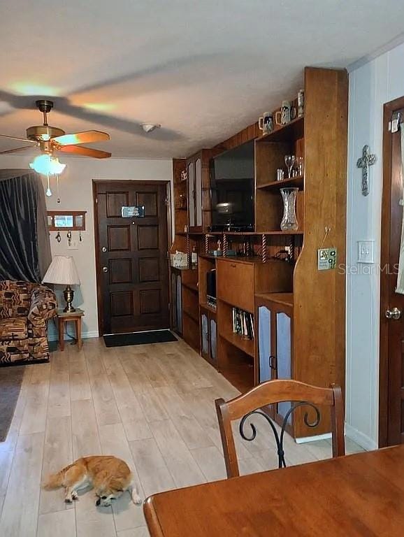 interior space with light wood-style flooring, baseboards, and a ceiling fan