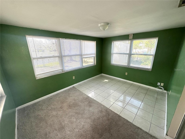 empty room with light tile patterned flooring, light carpet, and baseboards