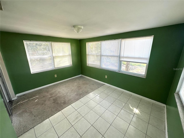 unfurnished room featuring light carpet, baseboards, and light tile patterned flooring