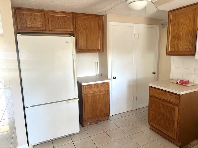 kitchen featuring brown cabinetry and freestanding refrigerator