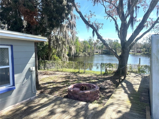 deck with a water view, an outdoor fire pit, and fence