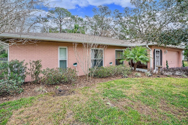 back of house featuring brick siding, a lawn, and an attached garage