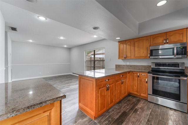 kitchen featuring stone countertops, a peninsula, dark wood-style flooring, visible vents, and appliances with stainless steel finishes