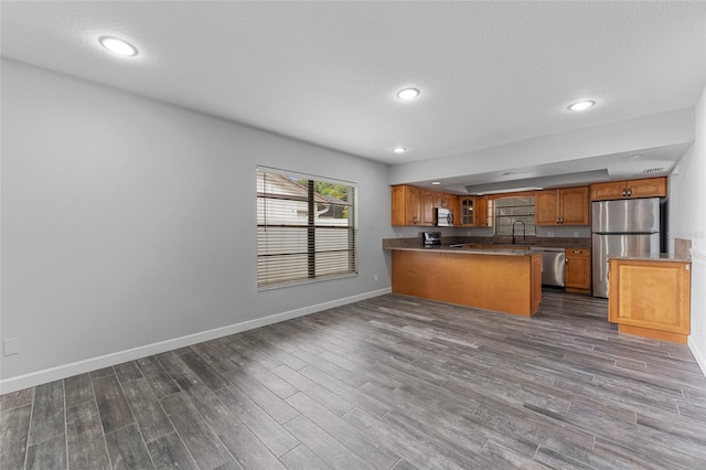 kitchen with dark wood-type flooring, appliances with stainless steel finishes, and brown cabinetry