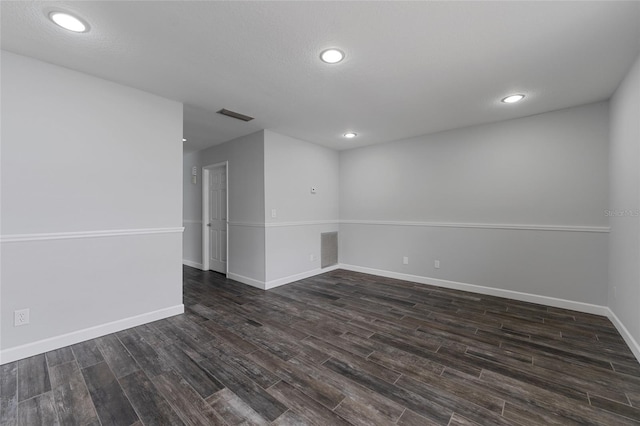 spare room featuring baseboards, visible vents, and dark wood-style flooring