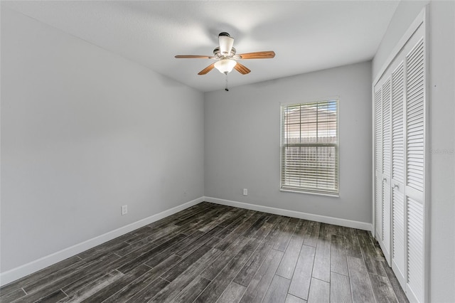 unfurnished bedroom with ceiling fan, a closet, baseboards, and dark wood-type flooring